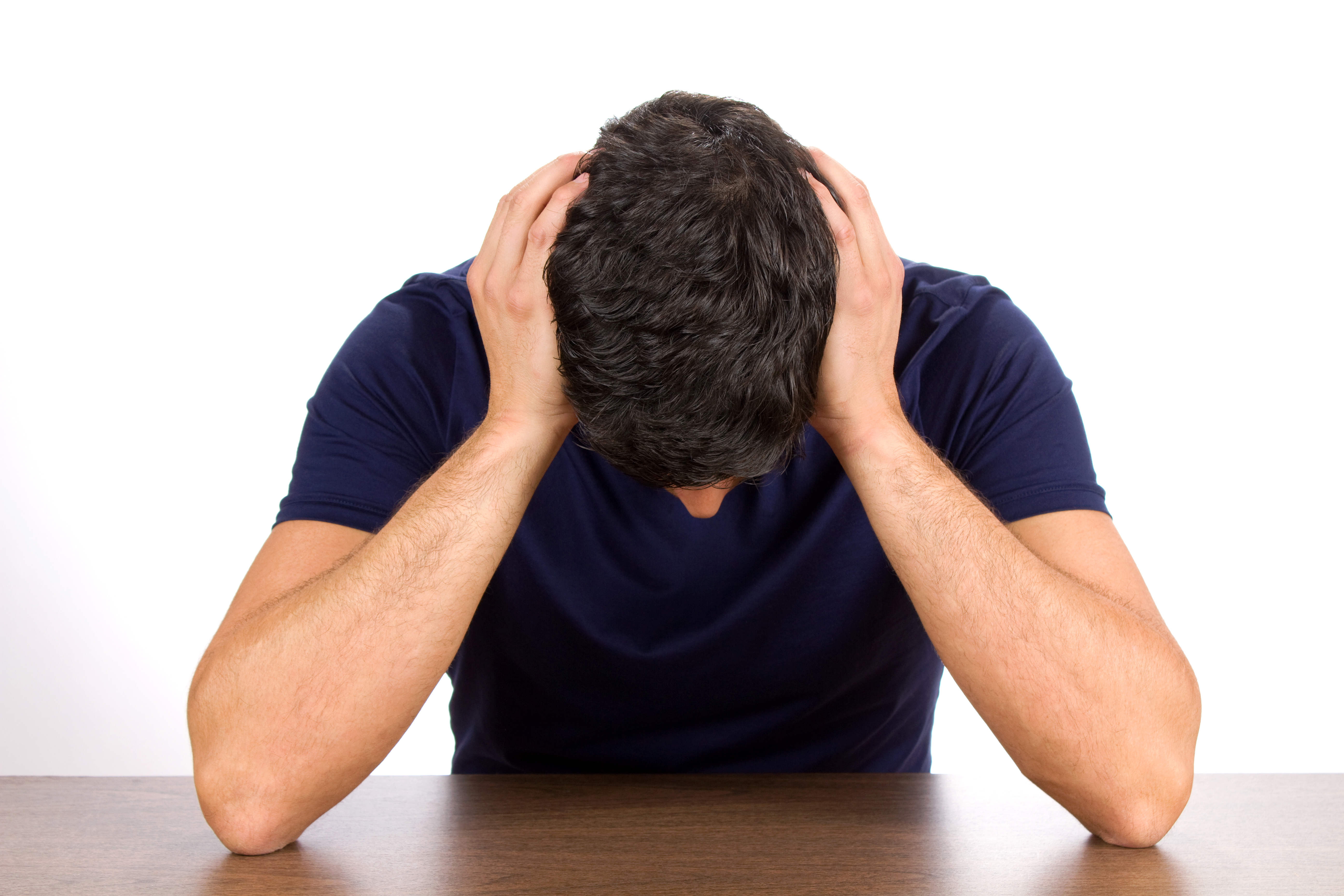 Downcast man holds his head as he suffers from depression and failure.