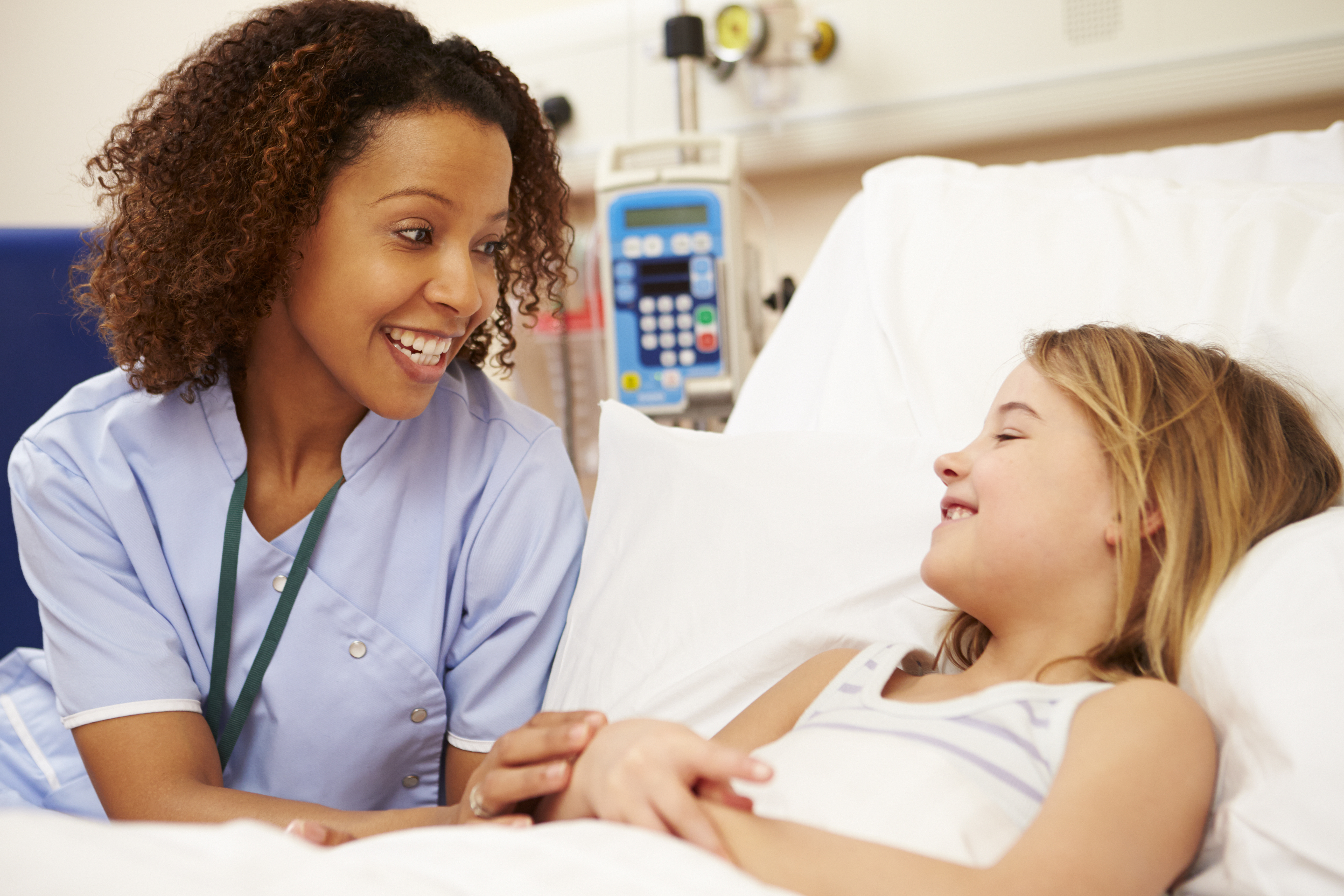 Nurse Sitting By Young Girl's Bed In Hospital