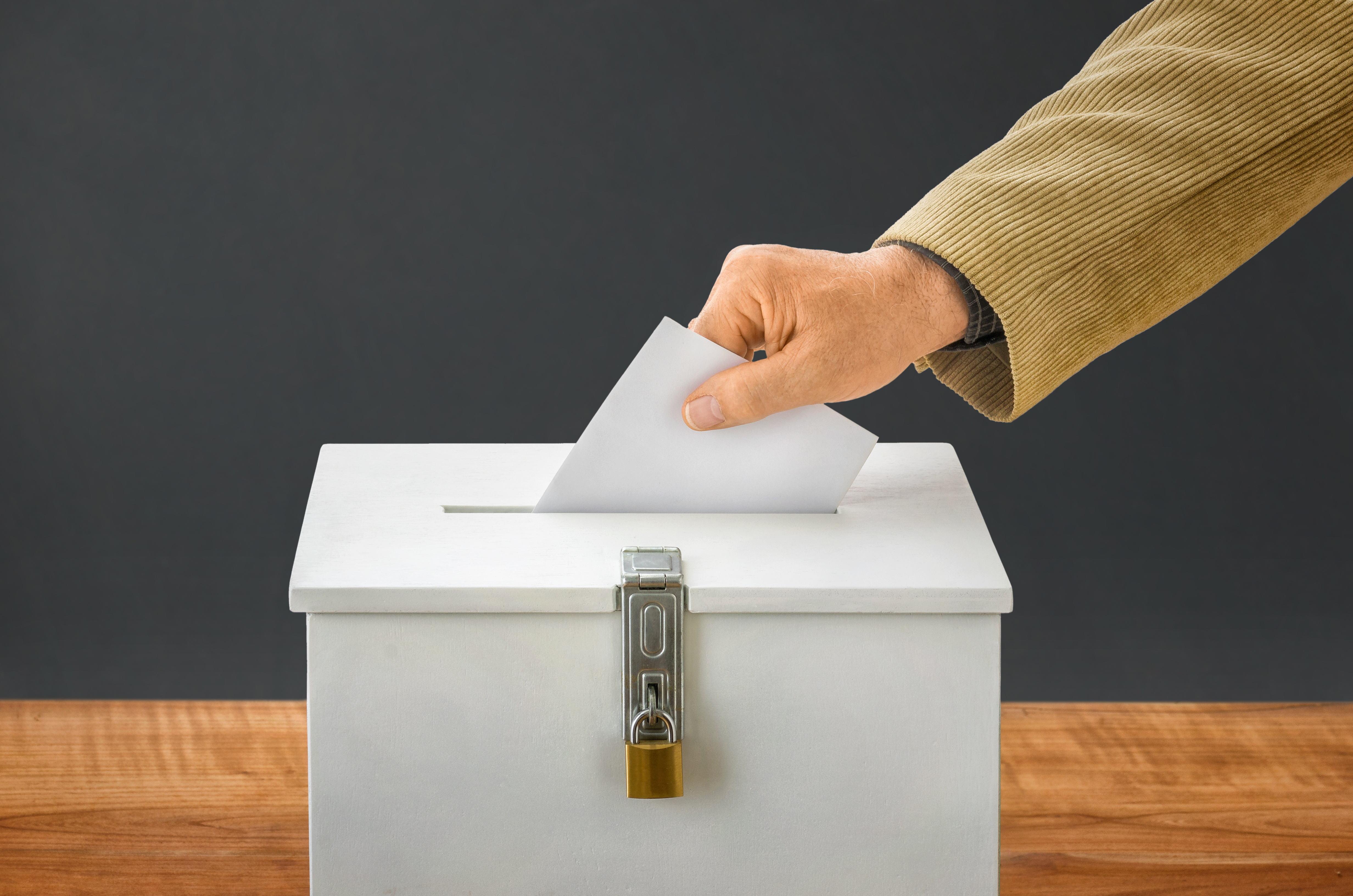 Mann wirft Stimmzettel in Wahlurne