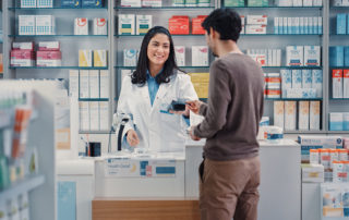 Pharmacy Drugstore: Man Chooses Medicine, Comes to the Counter, Talks to Beautiful Pharmacist Cashier, Pays for the Health Care Products at the Checkout Counter Using Contactless Payment Credit Card