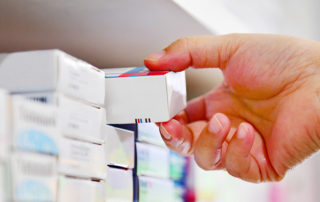 Closeup pharmacist hand holding medicine box in pharmacy drugsto