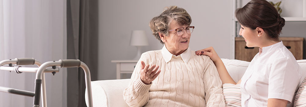 Senior older woman talking with female young caregiver