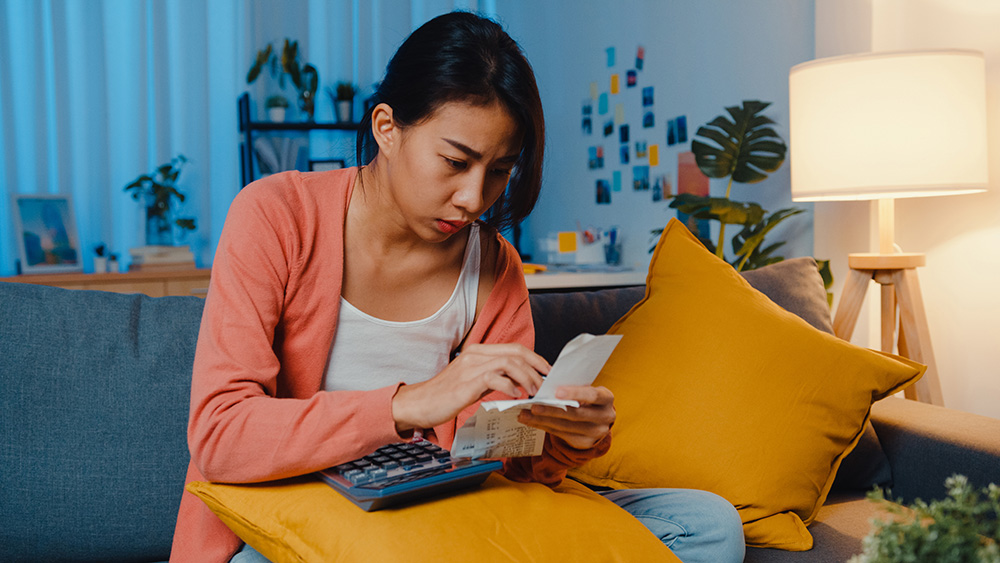 Asian lady feel stress and worried with bill and invoice credit card calculating loan on sofa at home. Home loan stress, Get loan no job,  Coronavirus hardship loans, Can't make loan payment concept.